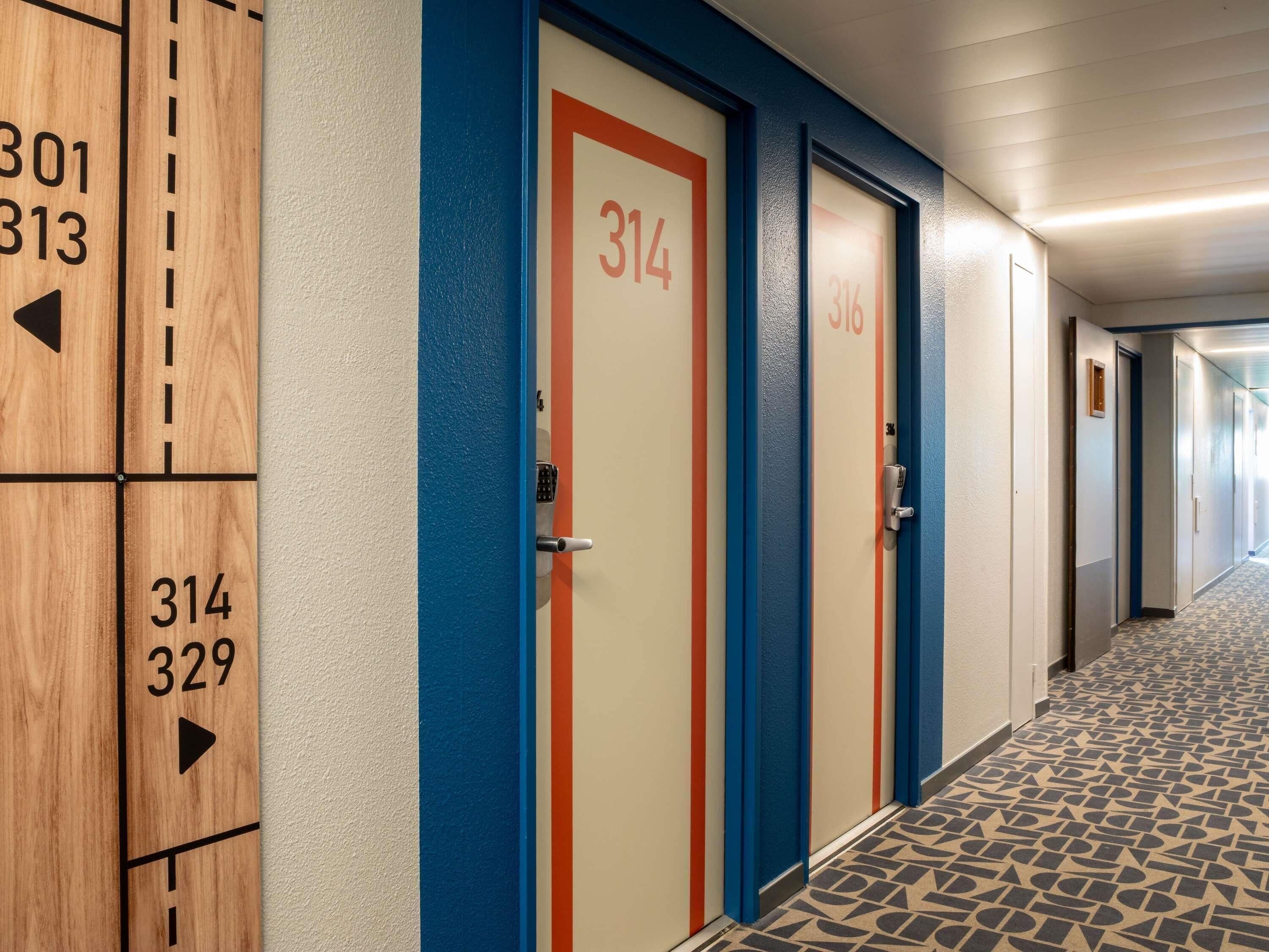 A hotel corridor with doors numbered 314 and 316, and a directional sign indicating room 329.
