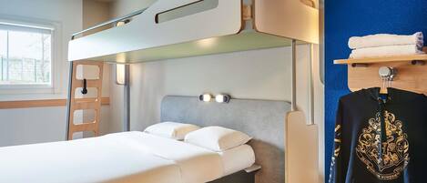 A bunk bed with a ladder, a bedside table, a wall-mounted light, and a window with a view.
