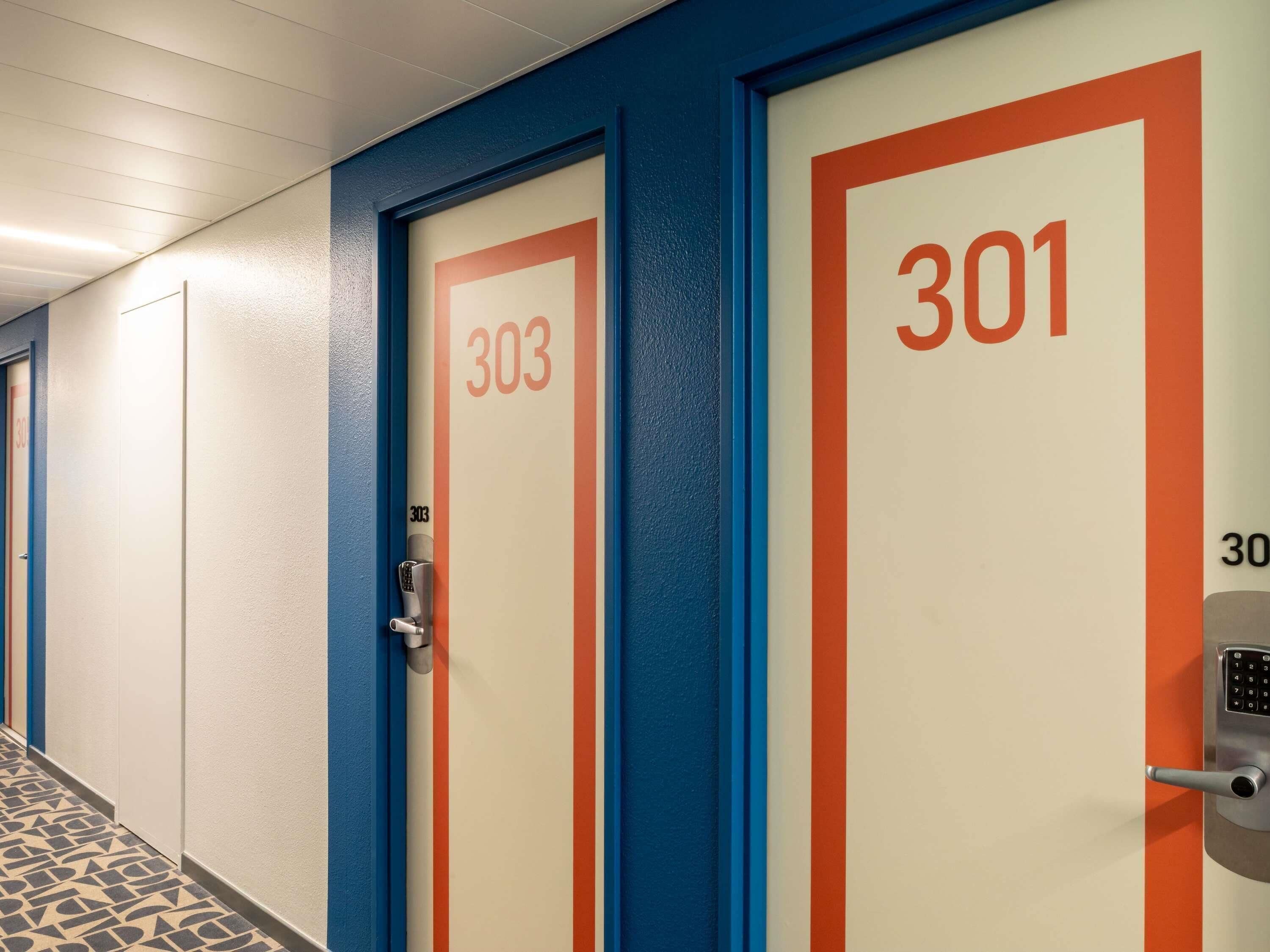 A hallway with doors numbered 303 and 301, featuring a modern design with blue and orange accents.
