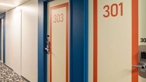 A hallway with doors numbered 303 and 301, featuring a modern design with blue and orange accents. - ibis budget Vélizy (Velizy-Villacoublay)