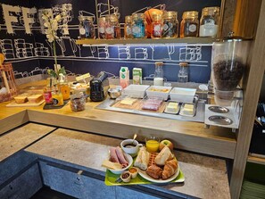 Un buffet de petit-déjeuner proposant une variété d’aliments, de condiments et une machine à café.