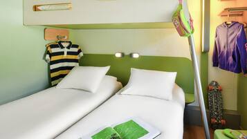 Una cama litera con dos almohadas blancas, una camisa a rayas colgada en la pared y un monopatín apoyado contra la pared.