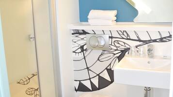 Une salle de bain avec une douche à parois de verre, des toilettes blanches, un lavabo avec un miroir et un mur d’accent bleu.