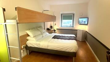 A bunk bed room with a desk and a television.