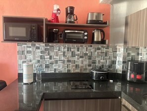 A kitchen with a microwave, toaster, coffee maker, and a slow cooker on the counter. - Cancun Plaza Condo Mexico (Cancun)