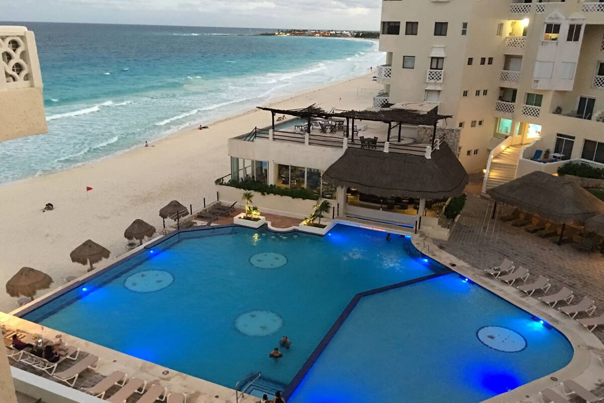 A pool area with lounge chairs and a view of the beach.