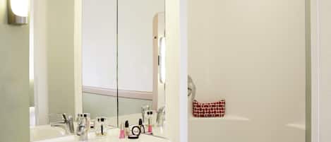 Une salle de bain avec un lavabo blanc, deux robinets, un miroir et un porte-serviettes.
