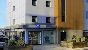 Un hotel moderno con un cartel llamativo de "ibis budget", una fachada limpia y una entrada acogedora con un amplio ventanal y un cartel.
