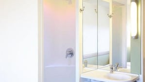 Un baño con bañera, un espejo grande y dos lavamanos.
