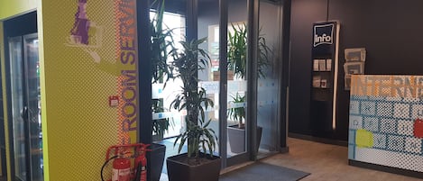 Zona d'arribada amb un extintor, una planta en test i una taula de recepció.