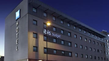 Ein modernes Hotelgebäude mit 'ibis budget' Schildern, zahlreichen Fenstern und einer glatten Fassade.