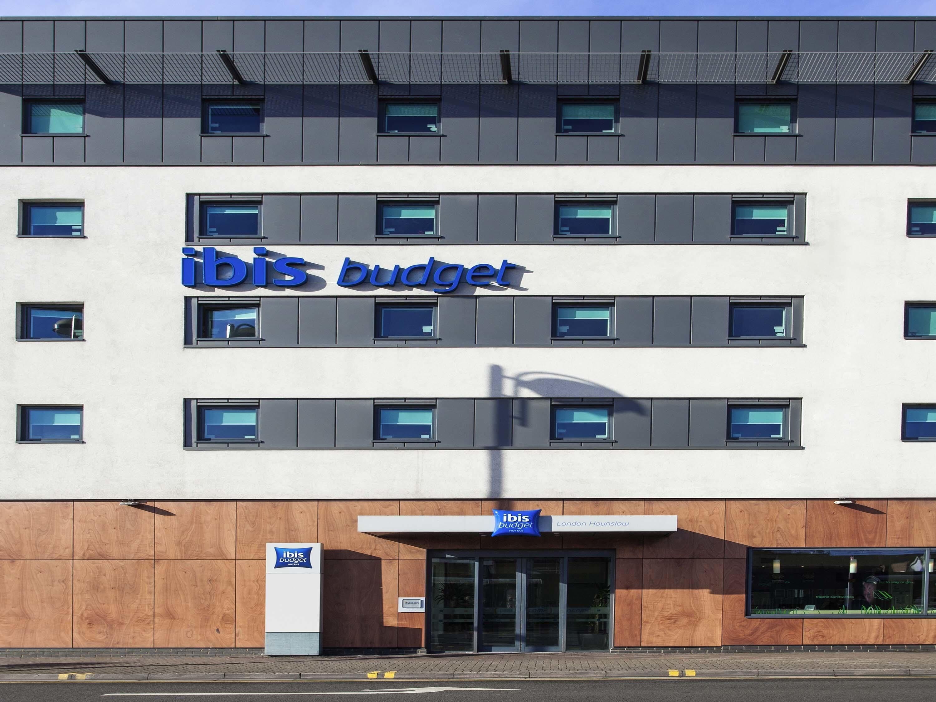 Un bâtiment moderne arborant l’enseigne « ibis budget », doté de nombreuses fenêtres et d’une façade en bois.