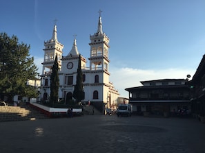 Une église historique dotée de trois tours et d’une horloge, entourée de rues pavées et de bâtiments traditionnels.