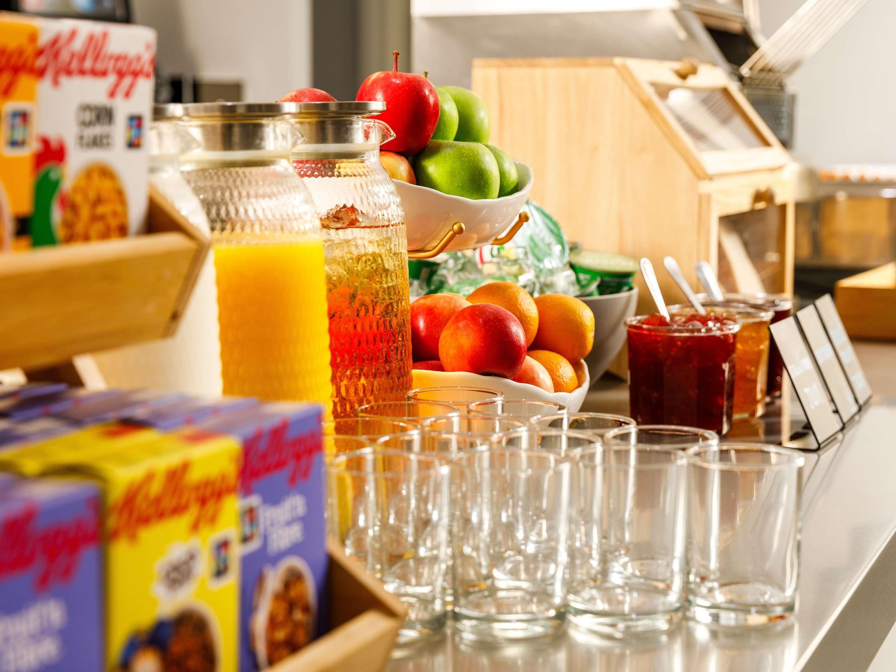 A breakfast buffet with cereal boxes, fruit, and beverages.