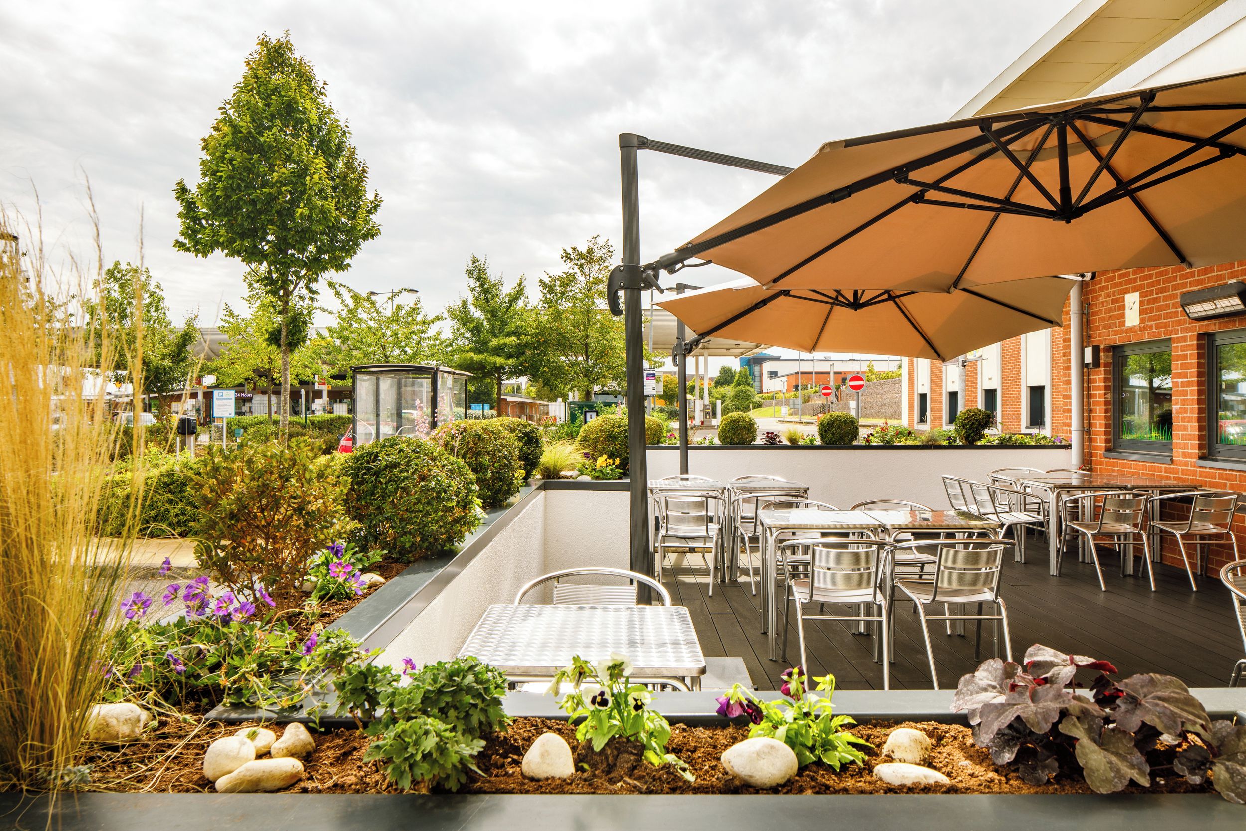 Una terrazza esterna con tavoli e sedie, circondata da fioriere e una zona relax coperta.