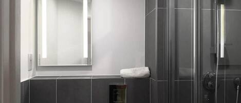 A modern bathroom with a glass-enclosed shower, a white sink, and a mirror above the sink.