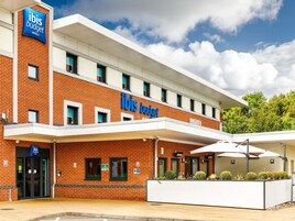 A two-story hotel with a prominent 'ibis budget' sign, a covered entrance, and a landscaped outdoor area.