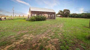 A rustic barn in a grassy field with a clear sky. - Abington Farm (Heyfield)