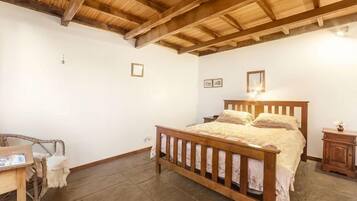 A bedroom with a wooden bed, a nightstand, a chair, and a small table.