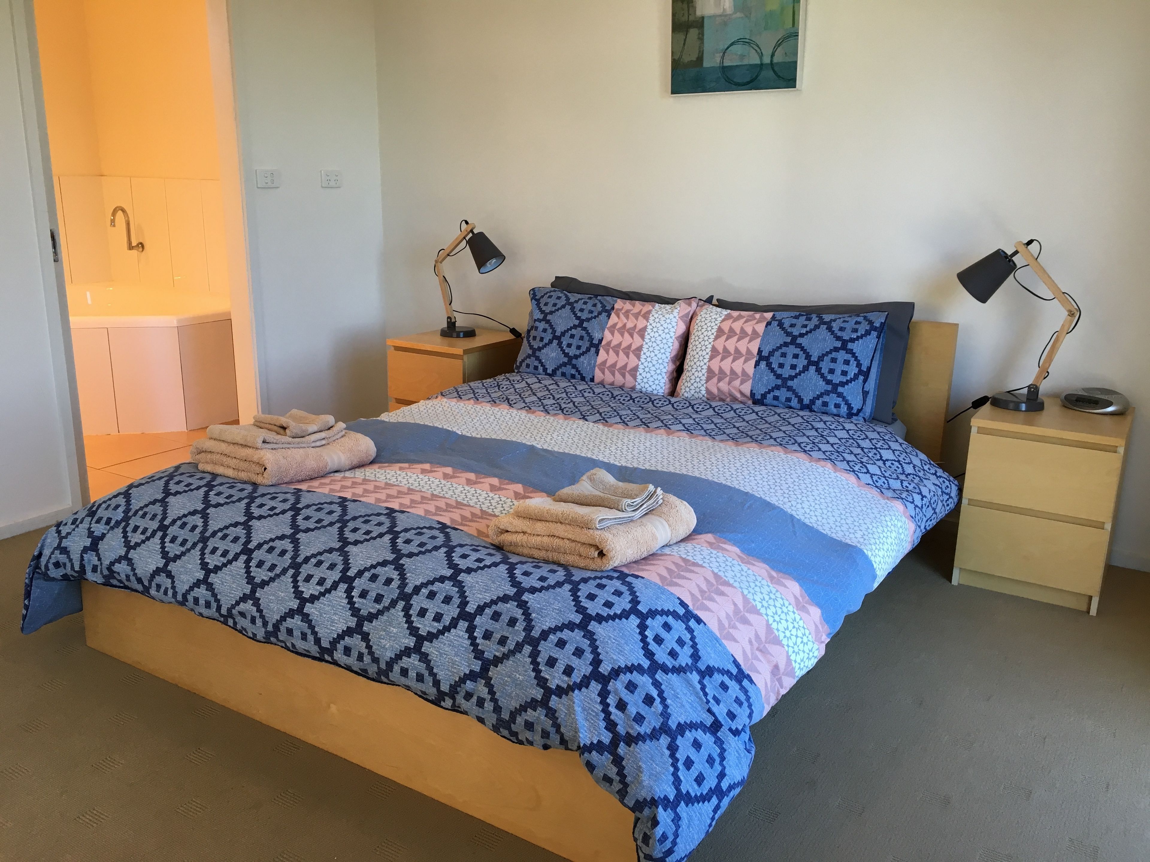 Una cama bien hecha con ropa de cama estampada y dos lámparas de noche.