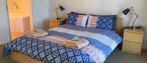 Una cama bien hecha con ropa de cama estampada y dos lámparas de noche.