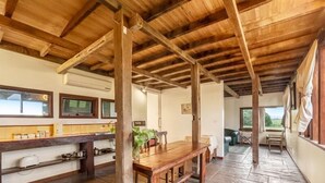 A spacious room with a wooden ceiling, a kitchen area with a long counter, and a dining table. - Abington Farm (Heyfield)