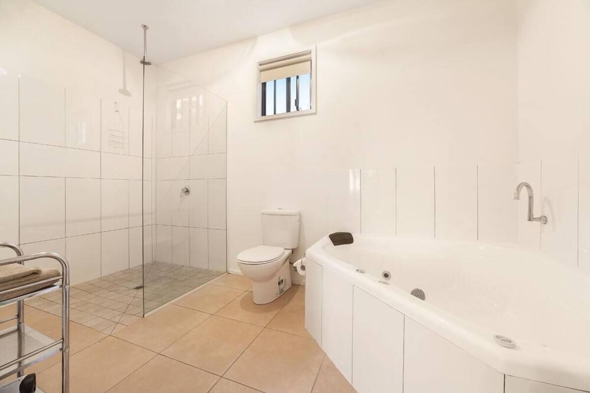 Un baño moderno con cabina de ducha de vidrio, inodoro y bañera independiente.