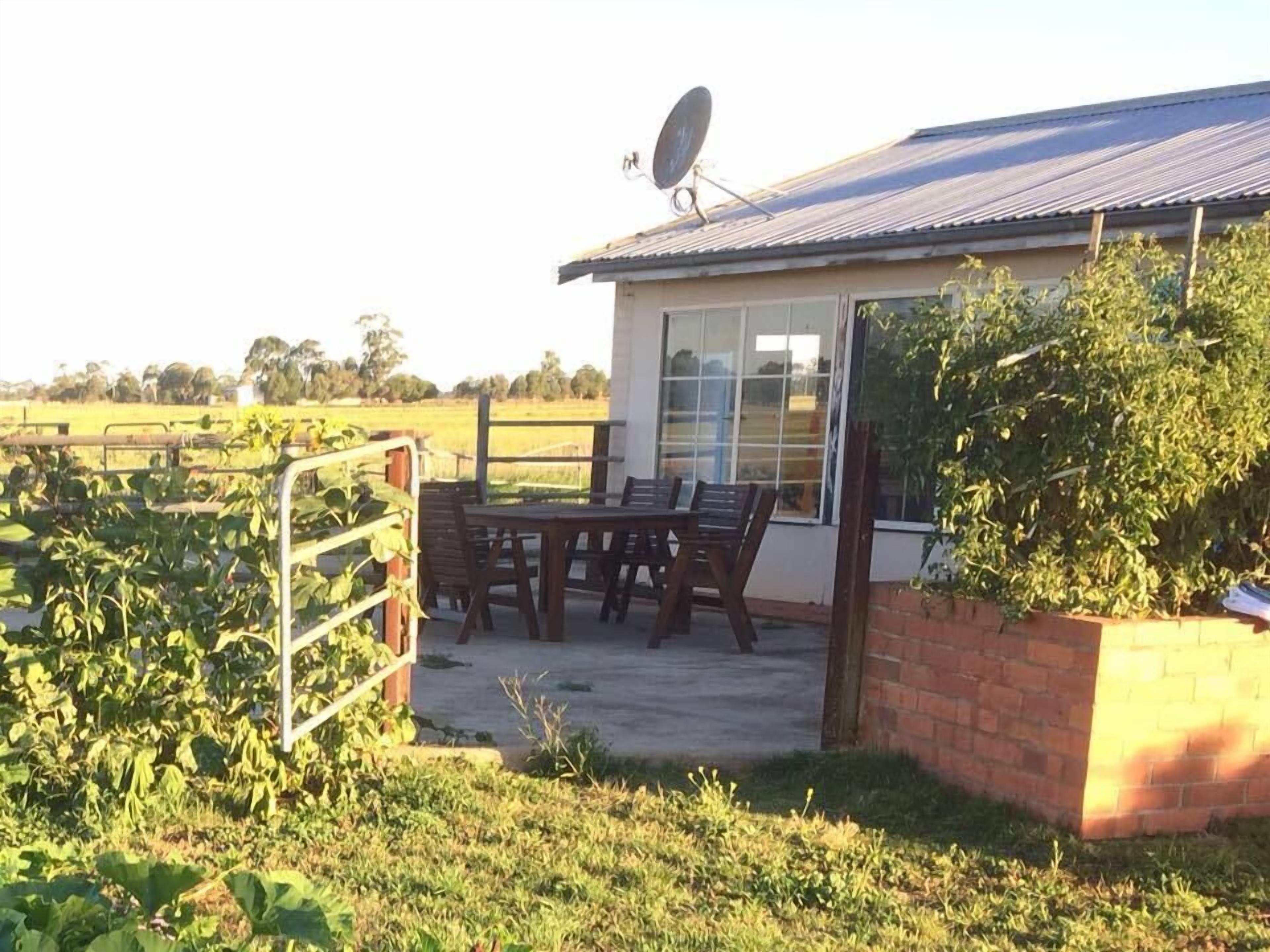 A small building with a patio, a satellite dish, and a view of a field.