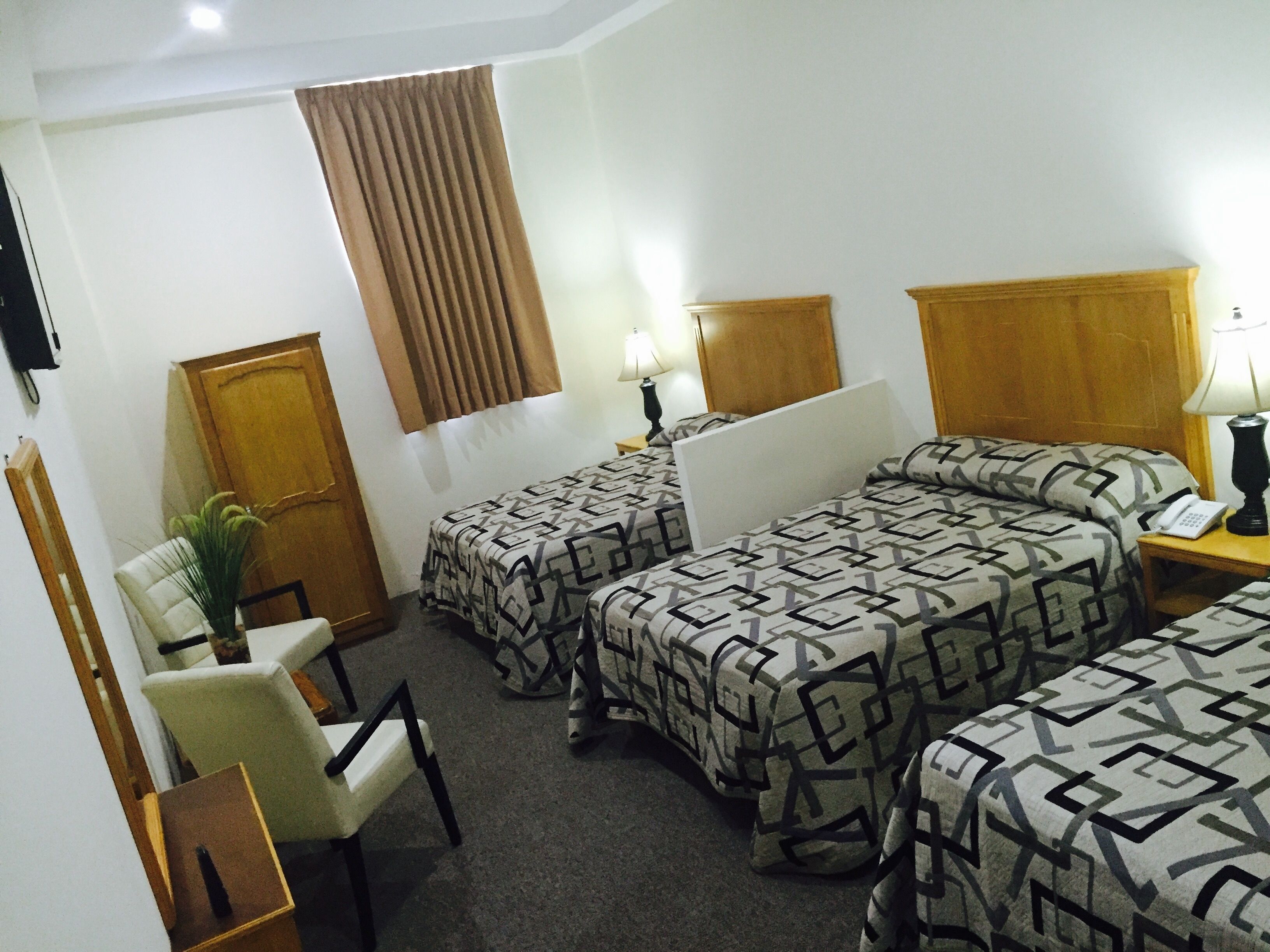 Une chambre d’hôtel avec deux lits simples, un bureau, une chaise, une lampe et un téléphone.