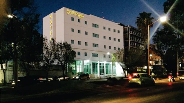 Un hotel de varios pisos con un llamativo letrero que dice 'HOTEL' en la fachada.