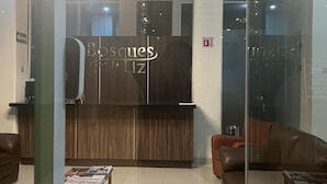 Una zona de recepción con un mostrador de madera, dos sofás de cuero y un atril para revistas.