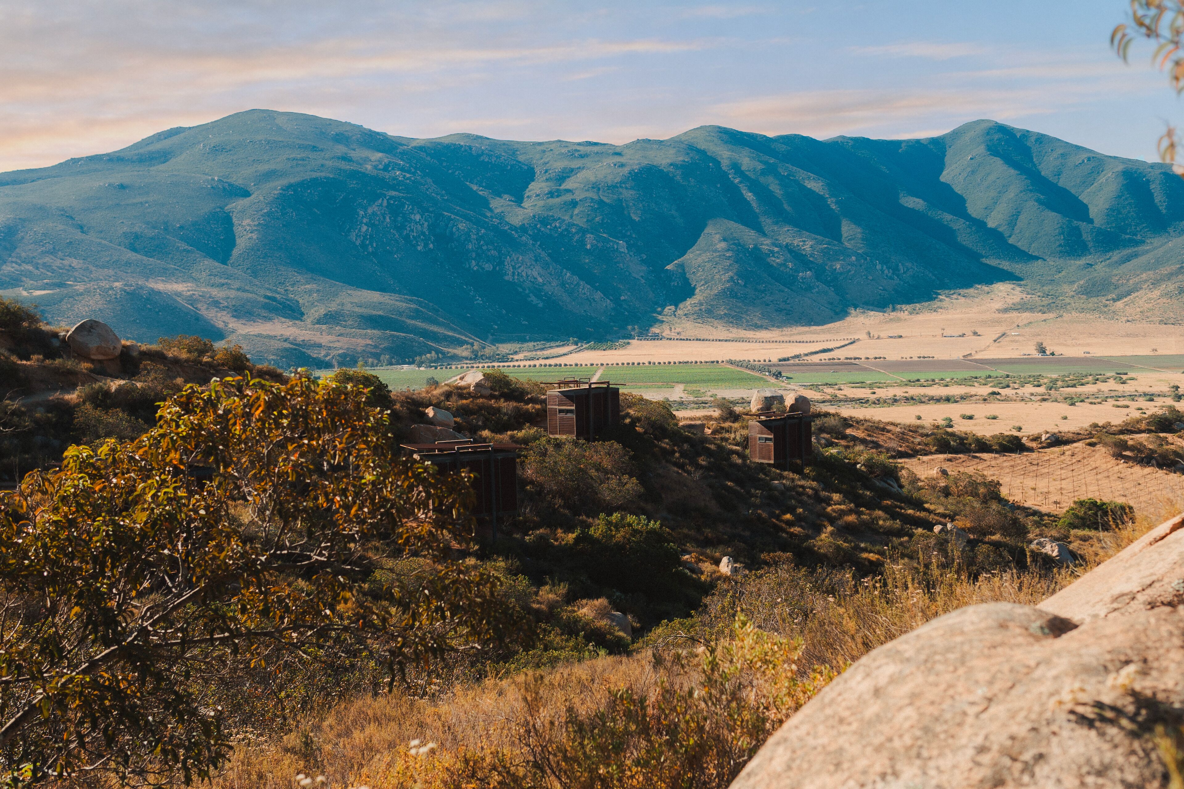 A mountainous landscape with a few buildings in the foreground.