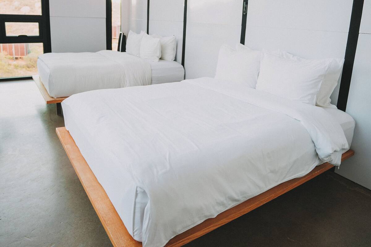 Un dormitorio moderno con dos camas, un ventanal y vistas al exterior.