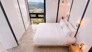 Un dormitorio con cama, mesita de noche y vistas al paisaje.