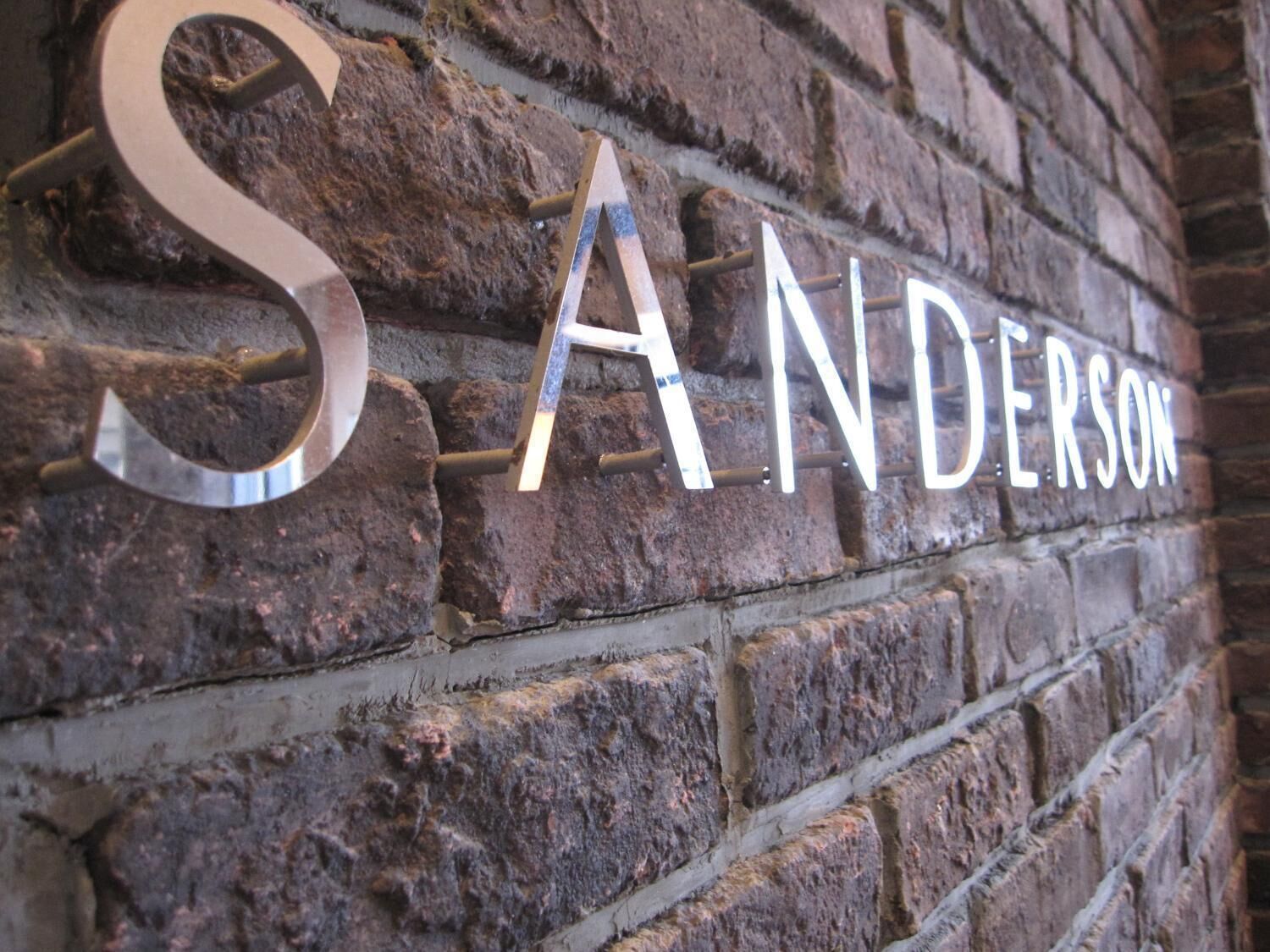 A brick wall with the name "SANDERSON" in large, metallic letters.
