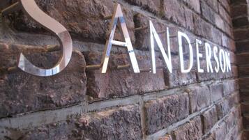 A brick wall with the name "SANDERSON" in large, metallic letters.