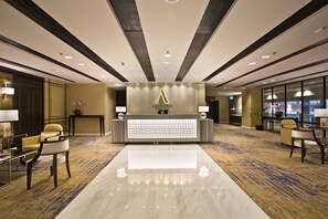 A hotel reception area with a modern design, featuring a reception desk, seating area, and a large window providing a view of the cityscape. -  Changi Transit Hotel (Singapore)