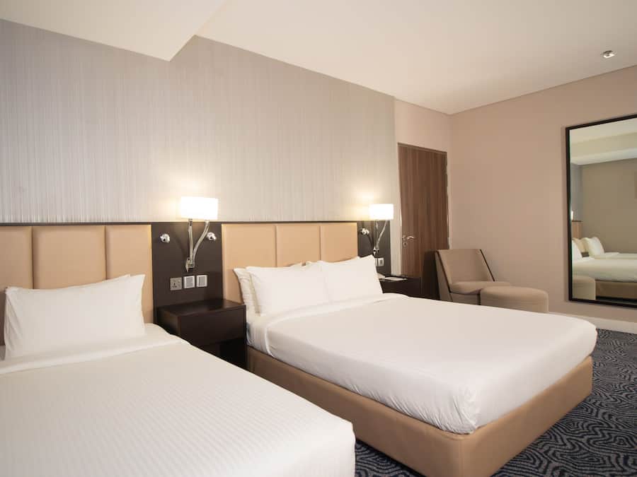 Una habitación de hotel con dos camas, una mesita de noche, una silla, un espejo y un ventanal grande.