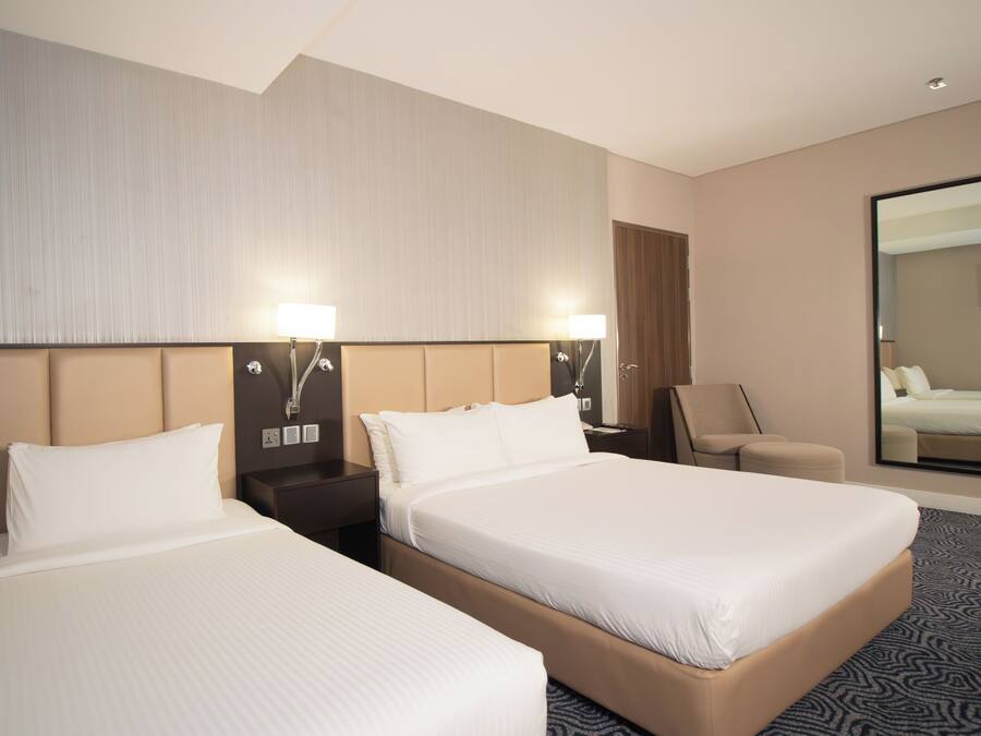 A hotel room with two beds, a nightstand, a chair, and a large mirror.