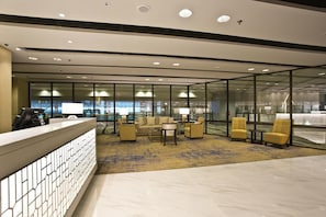 A modern lobby with a reception desk, seating area, and large windows offering views of the cityscape. -  Changi Transit Hotel Terminal 3 (Singapore)