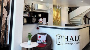 Ein Hotel-Empfangsbereich mit modernem Design, einer Treppe und einem Empfangstresen mit der Aufschrift 'HALO Boutique Hotel'.