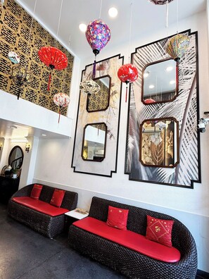 Un interior moderno con techo alto, faroles decorativos y una zona de estar con cojines rojos.