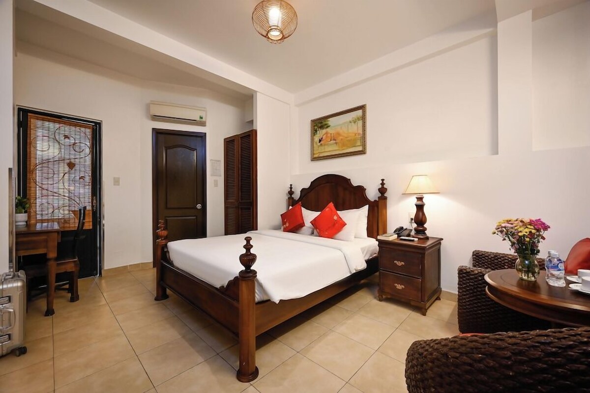 A neatly arranged bedroom with a wooden bed, bedside tables, a desk, and a chair.