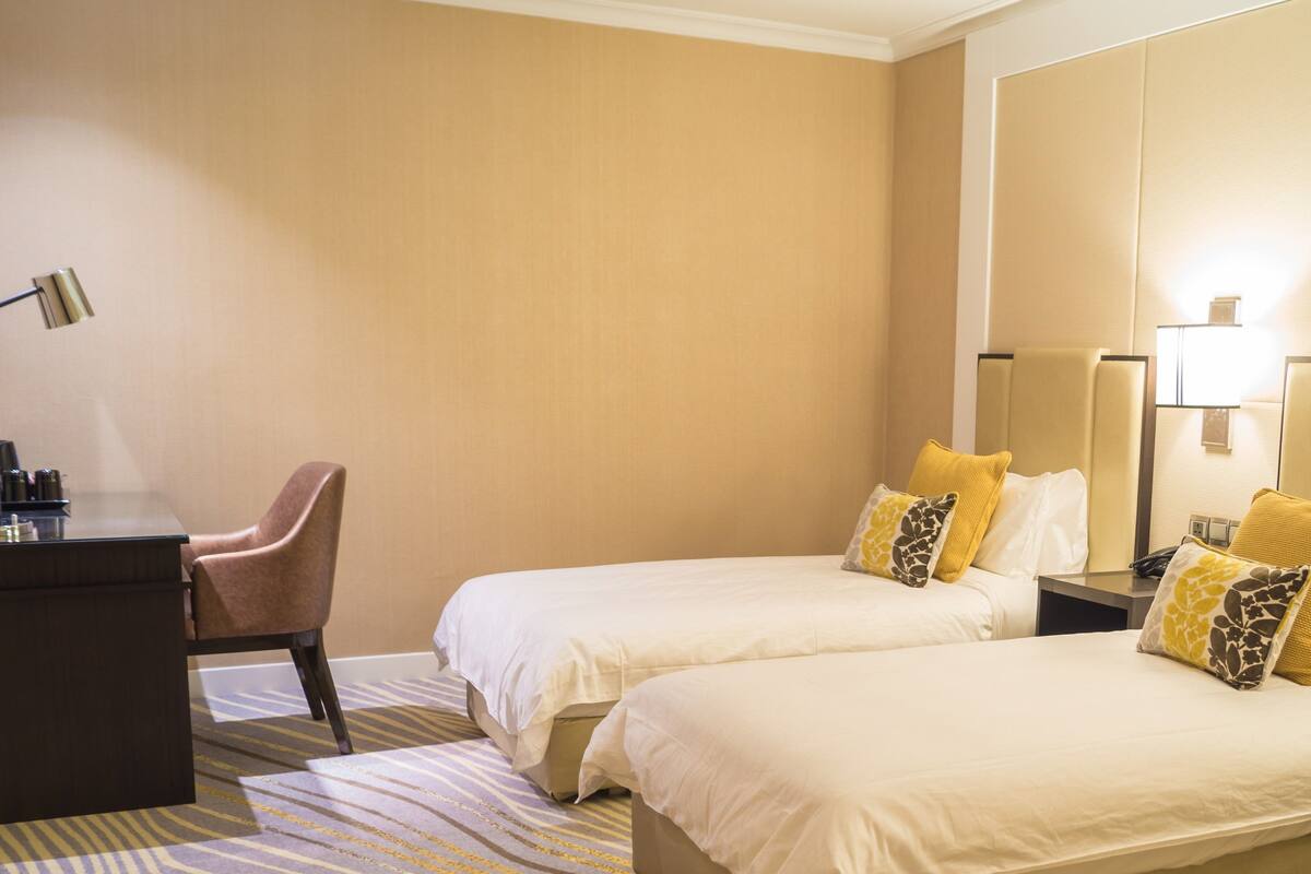 A hotel room with two beds, a desk, and a chair.