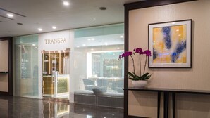 Un moderno vestíbulo de hotel con una tienda TRANSPA, un suelo de mármol pulido y un cuadro abstracto enmarcado.