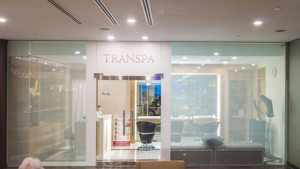 Un salón de TransSpa con una zona de recepción, una silla negra y un espejo grande.