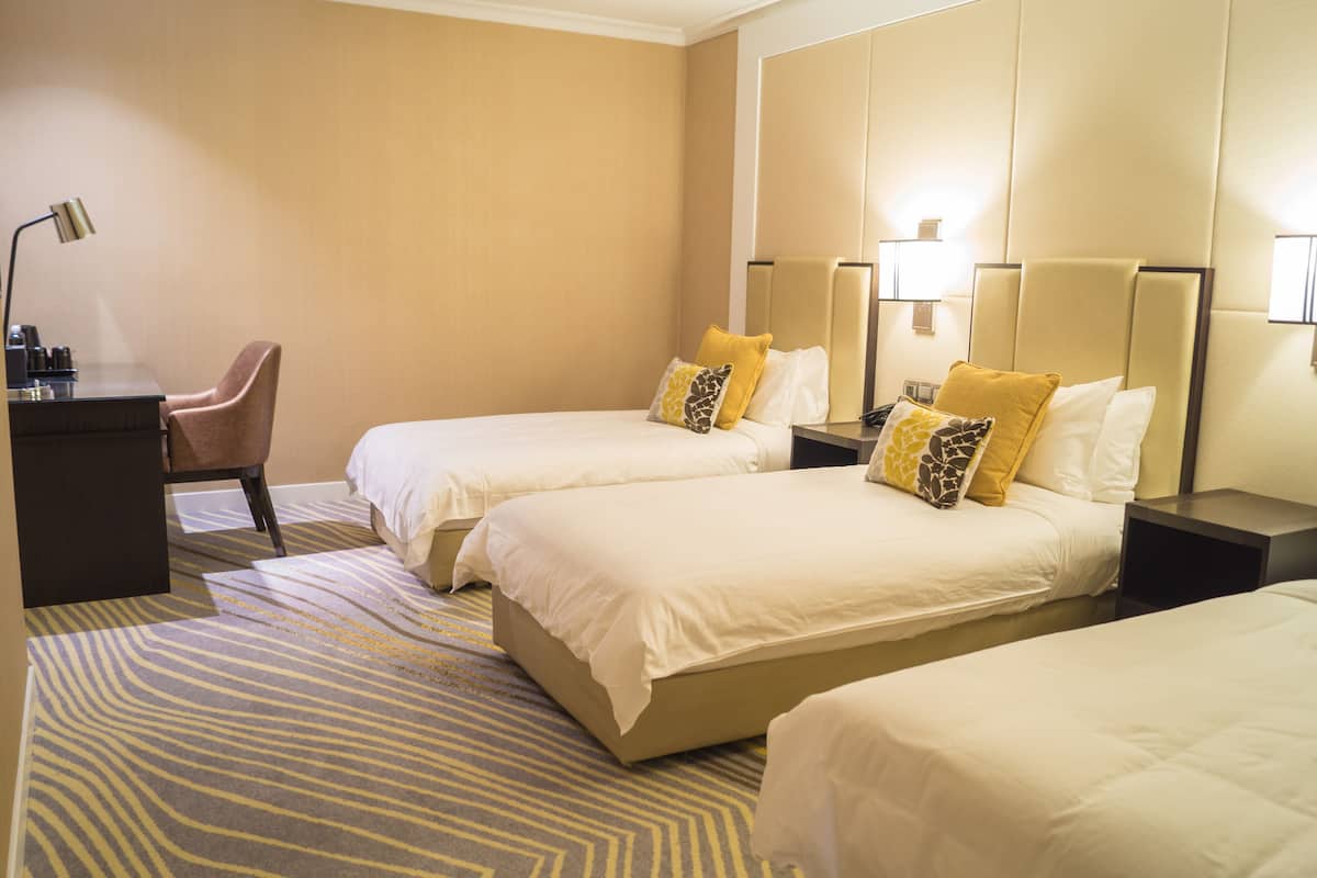 A hotel room with two beds, a desk, and a chair.