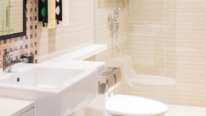 Un baño moderno con cabina de ducha de vidrio, un lavabo blanco y un inodoro.