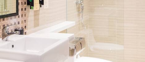Un baño moderno con cabina de ducha de vidrio, un lavabo blanco y un inodoro.