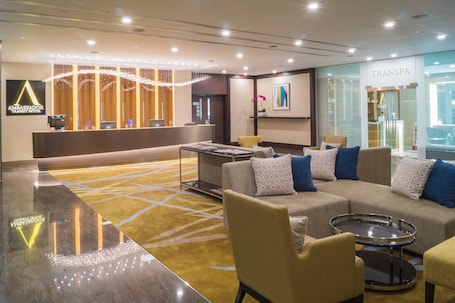 A modern hotel lobby with a reception desk, seating area, and a TransSpa spa.